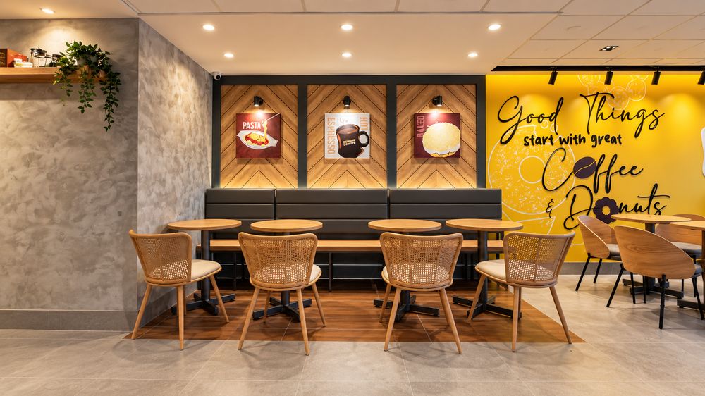 Restaurant dining area with rattan chairs, banquette seating, and a feature wall